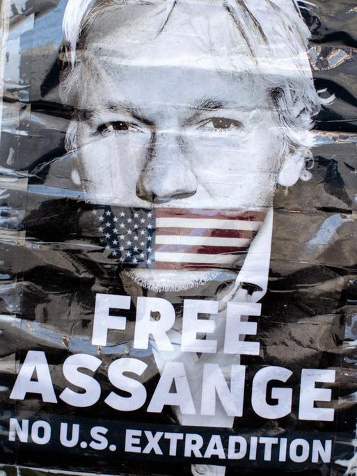 Plakat mit einem Porträt von Julian Assange mit der amerikanischen Fahne als Knebel über seinem Mund. Protestschild vor der ecuadoranischen Botschaft in London von April 2019.
