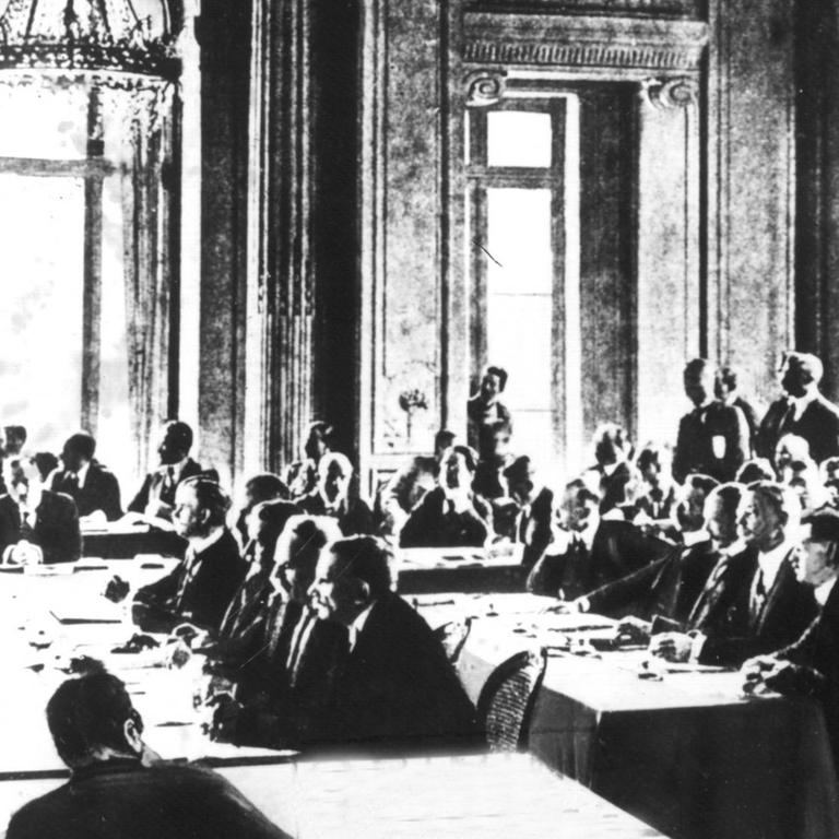 Die Sitzung vom 7. Mai 1919, in der der Vertragstext der deutschen Delegation zugestellt wurde. Der Versailler Vertrag war der wichtigste der Pariser Vorortverträge, die 1919/20 den 1. Weltkrieg beendeten. Der Versailler Vertrag wurde am 28.6.1919 im Versailler Schloß zwischen Deutschland und 27 alliierten und assoziierten Mächten unterzeichnet und trat am 20.1.1920 in Kraft. Ohne deutsche Beteiligung wurde ab dem 18.1.1919 in Paris der Text des Friedensvertrages zwischen Wilson, Lloyd George, Clemenceau und Orlando (Die "Großen Vier") ausgearbeitet. Am 7.5.1919 wurde der Text der Deutschen Delegation zugestellt 