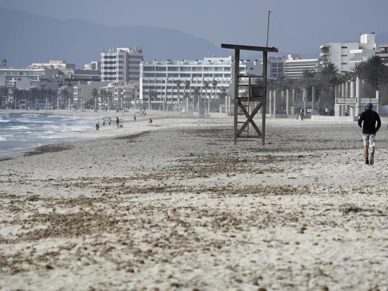 Ein Mann geht am Strand von Arenal auf Mallorca über den Sand. Deutsche Reiseveranstalter hoffen, dass sie Urlauber ab den Osterferien wieder nach Mallorca bringen können.