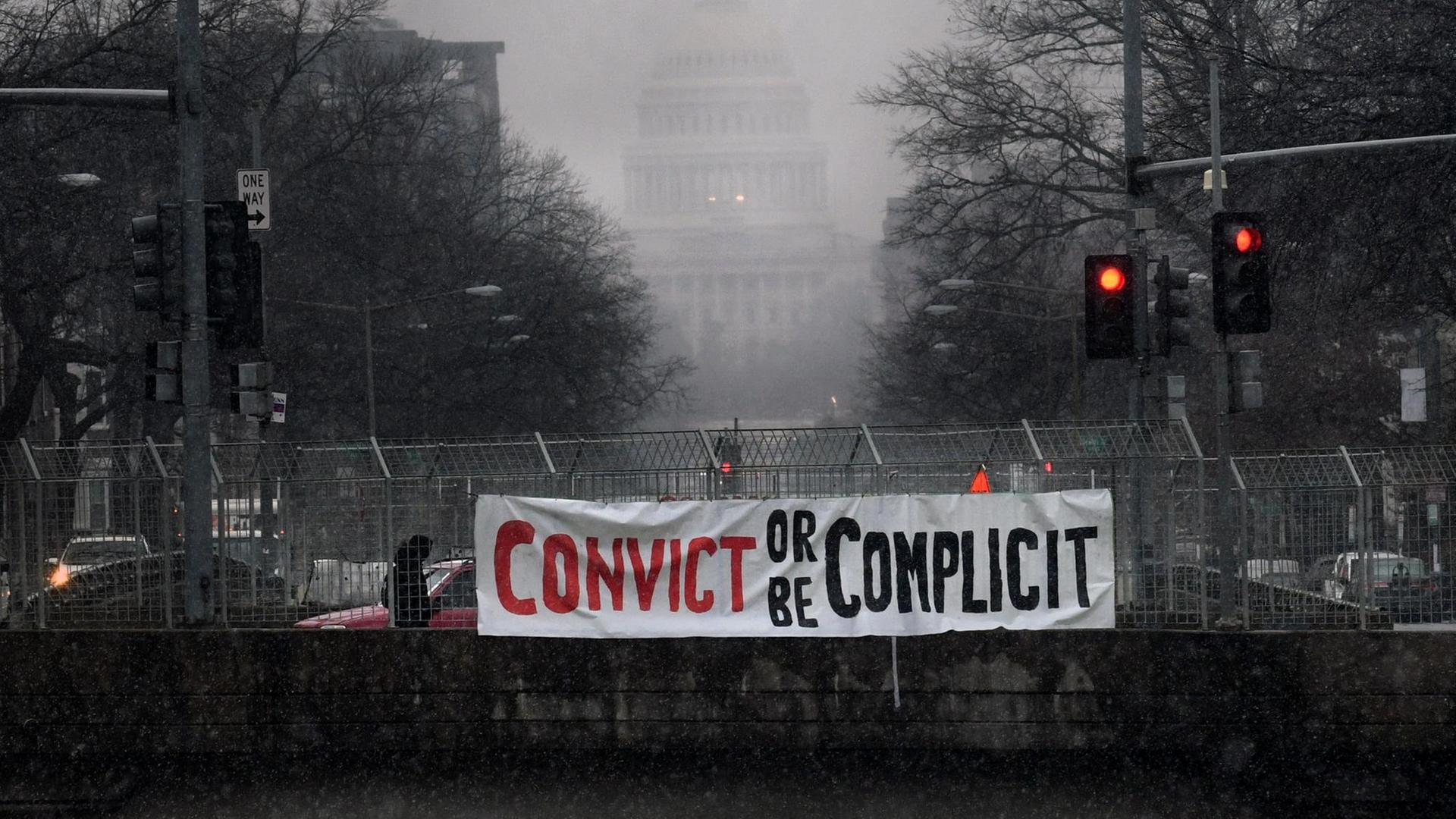 "Verurteilt ihn oder macht euch mitschuldig" steht auf einem Banner, das Aktivisten an einer Brücke vor dem Kapitol in Washington