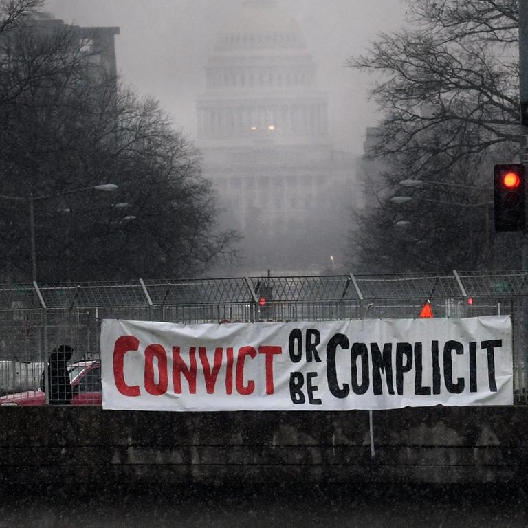 "Verurteilt ihn oder macht euch mitschuldig" steht auf einem Banner, das Aktivisten an einer Brücke vor dem Kapitol in Washington aufgehängt haben
