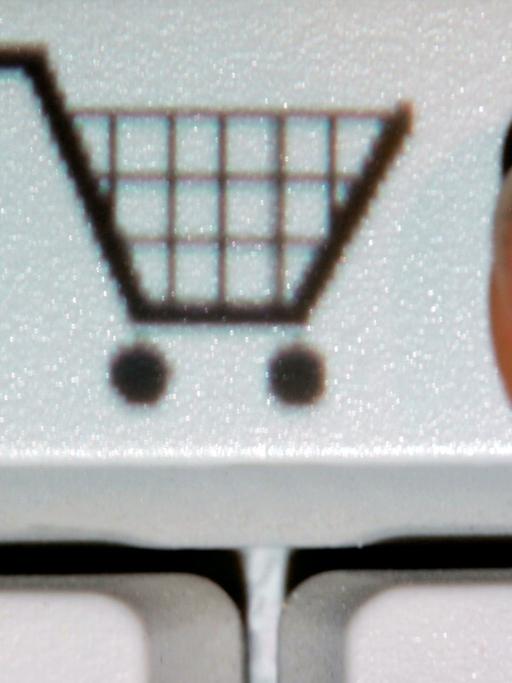 Ein Finger zeigt auf das Symbol eines Einkaufwagens auf einer Taste einer Computertastatur (gestelltes Foto).