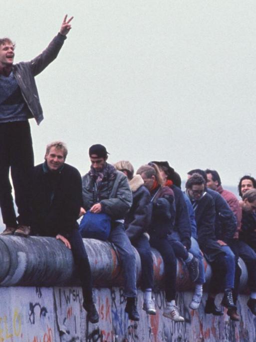 Westdeutsche sitzen am 27.9.1999 auf der Berliner Mauer und feiern die Grenzöffnung.