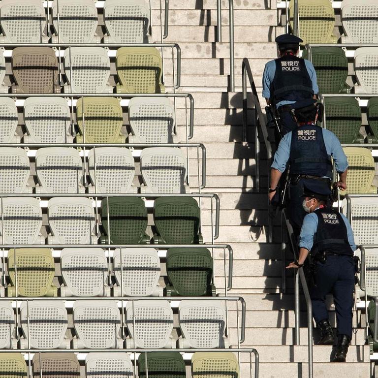Eröffnungsfeier im Olympiastadion von Tokio. Polizisten gehen die leere Tribüne hoch.