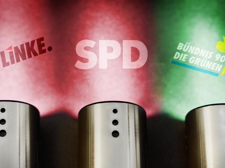 Sie sehen Taschenlampen mit rot-rot-grünen Lichtern, im Hintergrund die Schriftzüge "Die Linke", "SPD" und "Bündnis90 Die Grünen".