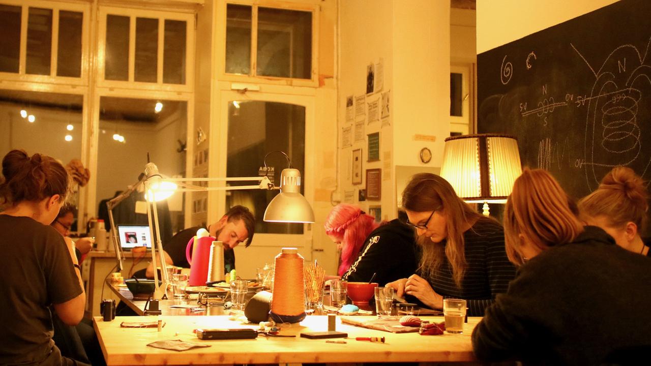 Mehrere Teilnehmer eines workshops nähen konzentriert an einem großen Werkstatt-Tisch