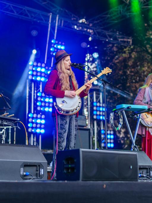 Eine Band, bestehend aus zwei Frauen und zwei Männern, steht auf einer Festivalbühne und spielt.