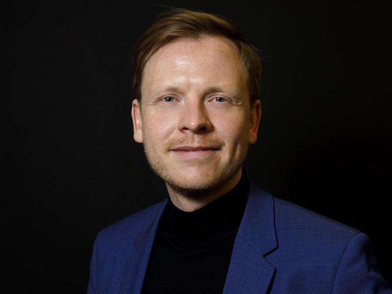 Markus Gabriel steht vor schwarzem Hintergrund und blickt freundlich in die Kamera.