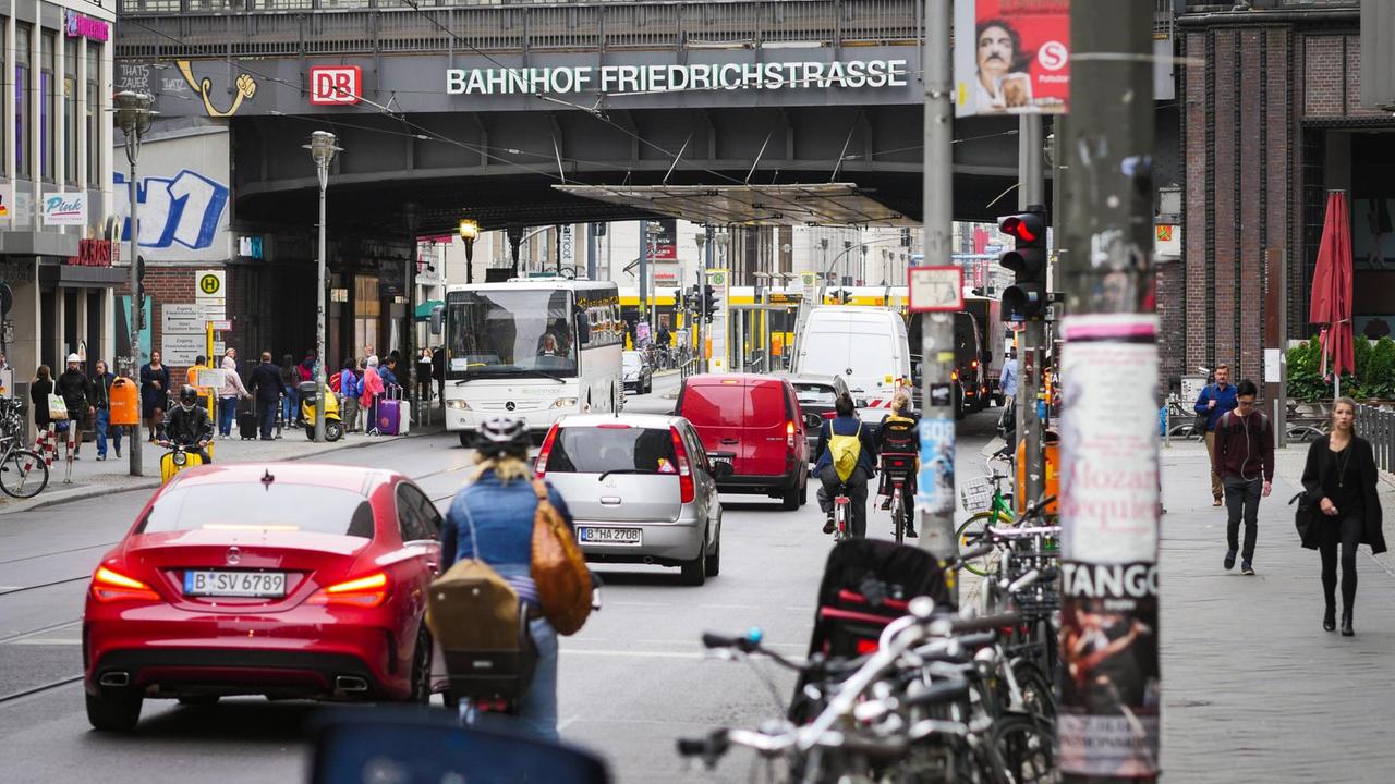 Unter der Brücke vom Bahnhof Friedrichstrasse führt eine Strasse hindurch, die dicht mit Autos, Radfahrern und Bussen gefüllt ist.