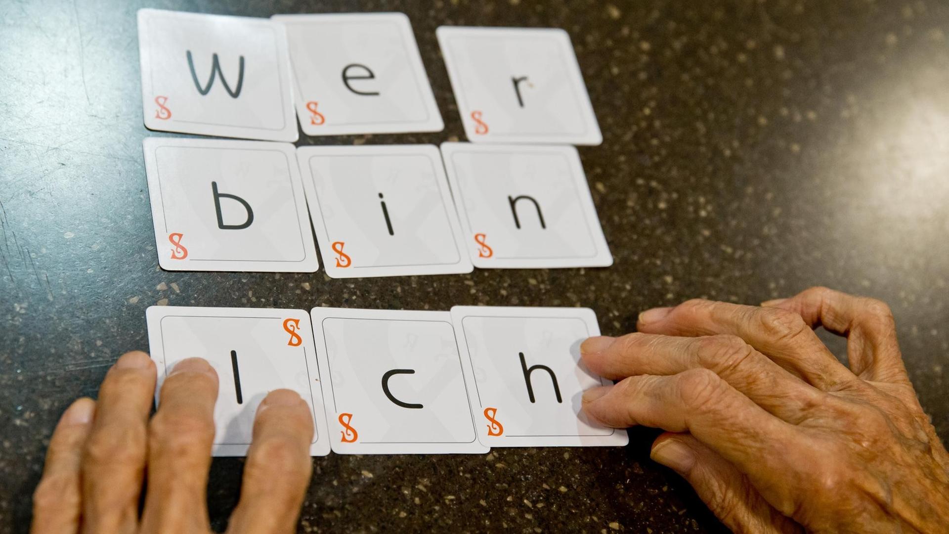 Eine Demenzkranke Frau legt die Karten eines Spiels zu dem Satz "wer bin ich" zusammen.