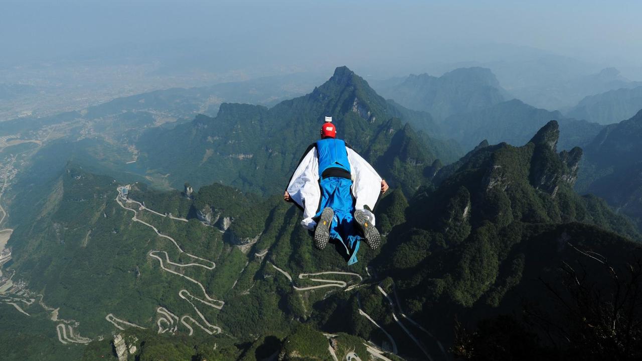 Ein Mann fliegt mit einem Wingsuit über eine chinesische Berglandschaft
