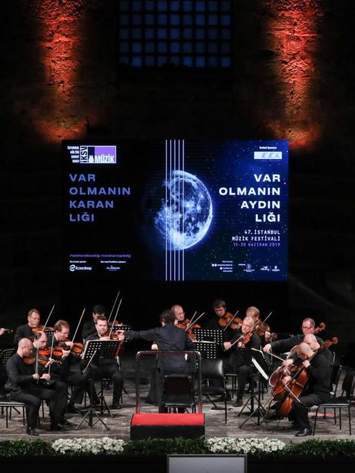 Ein Kammerorchester auf einer Bühne, die im Hintergrund das Logo das Festivals zeigt.