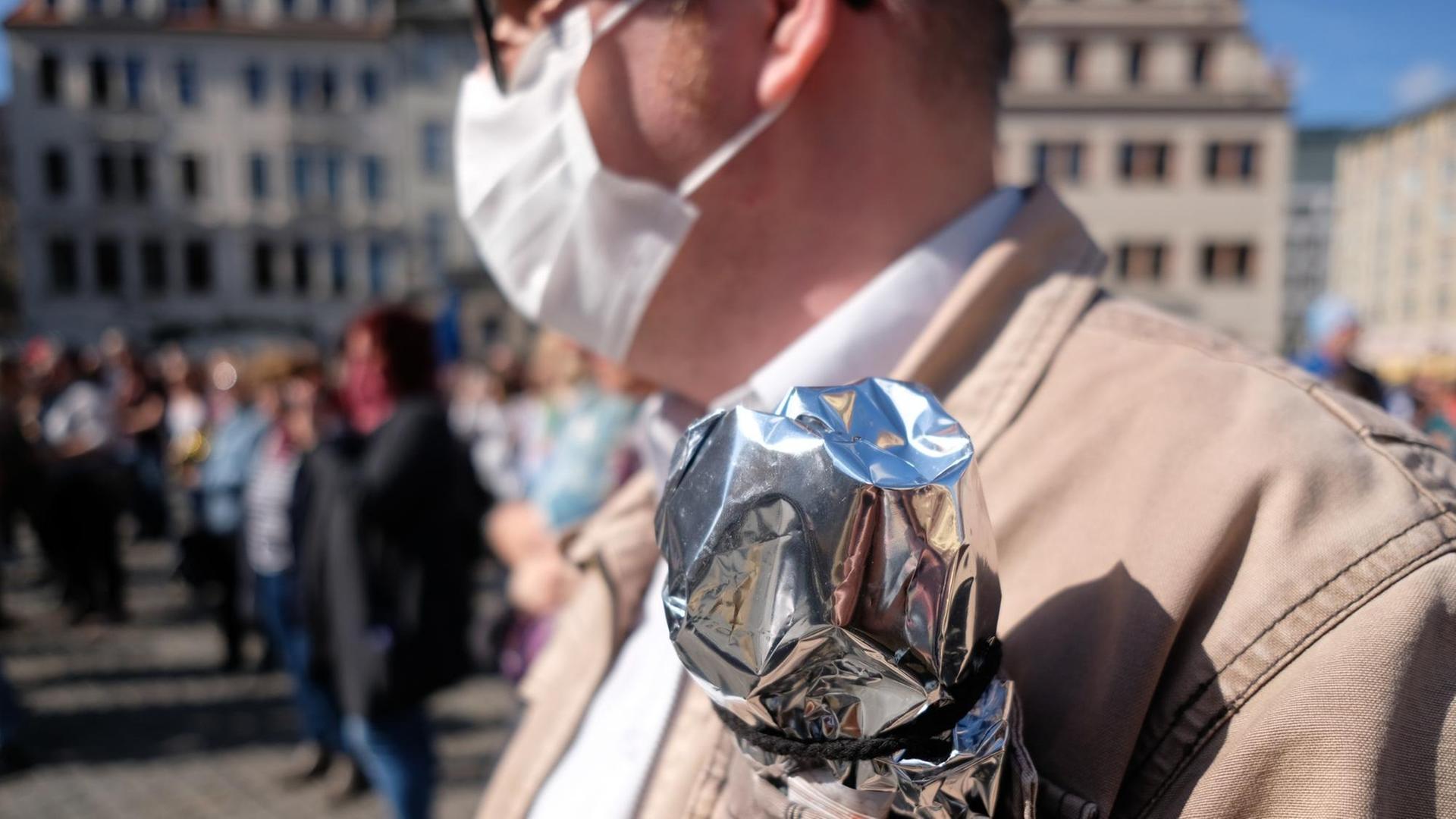 Leipzig: Ein Teilnehmer einer Demonstration gegen die Corona-Maßnahmen trägt Silberfolie in der Brusttasche