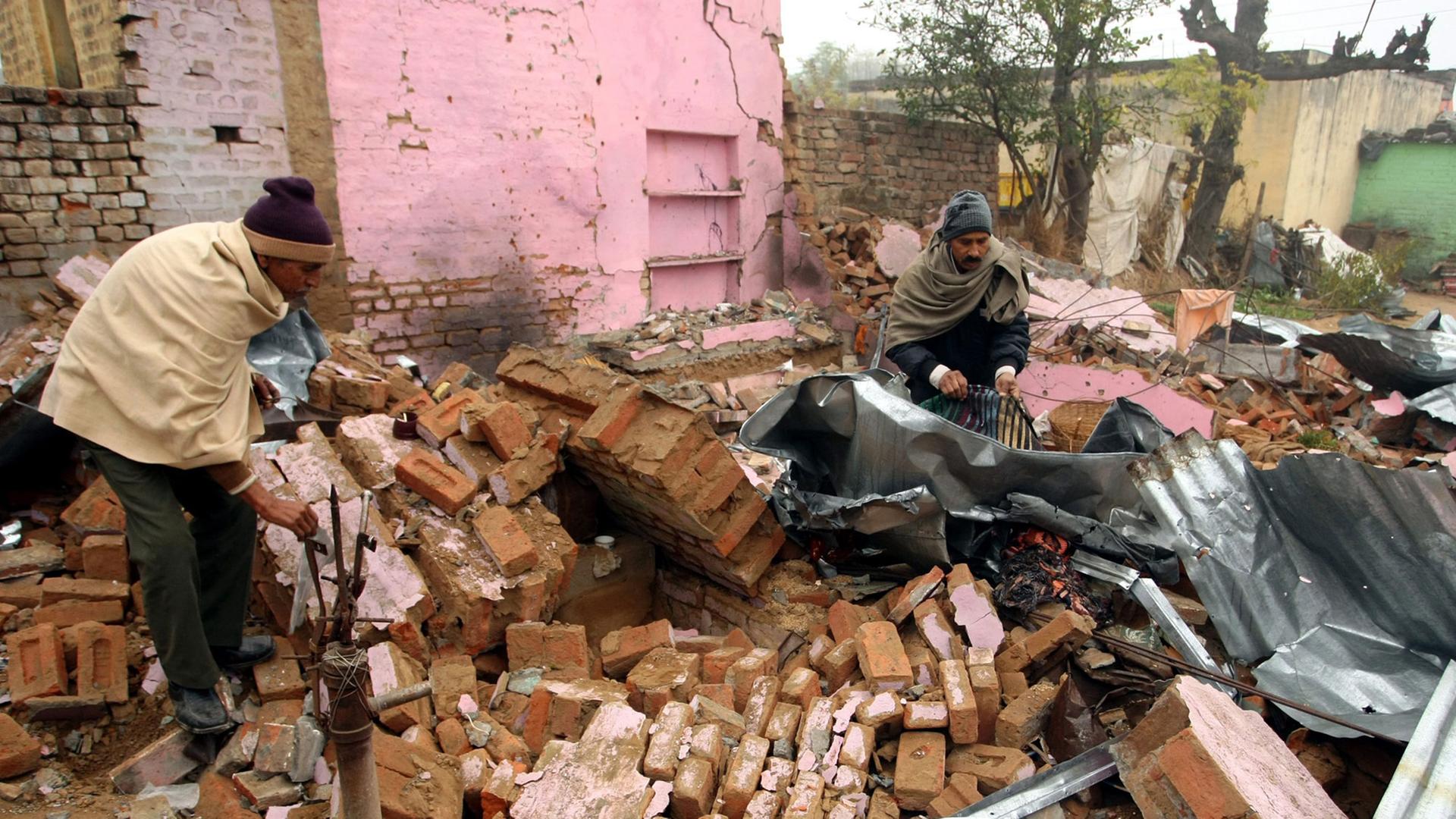 Einwohner der Kaschmir-Region suchen in Trümmern nach Gegenständen.
