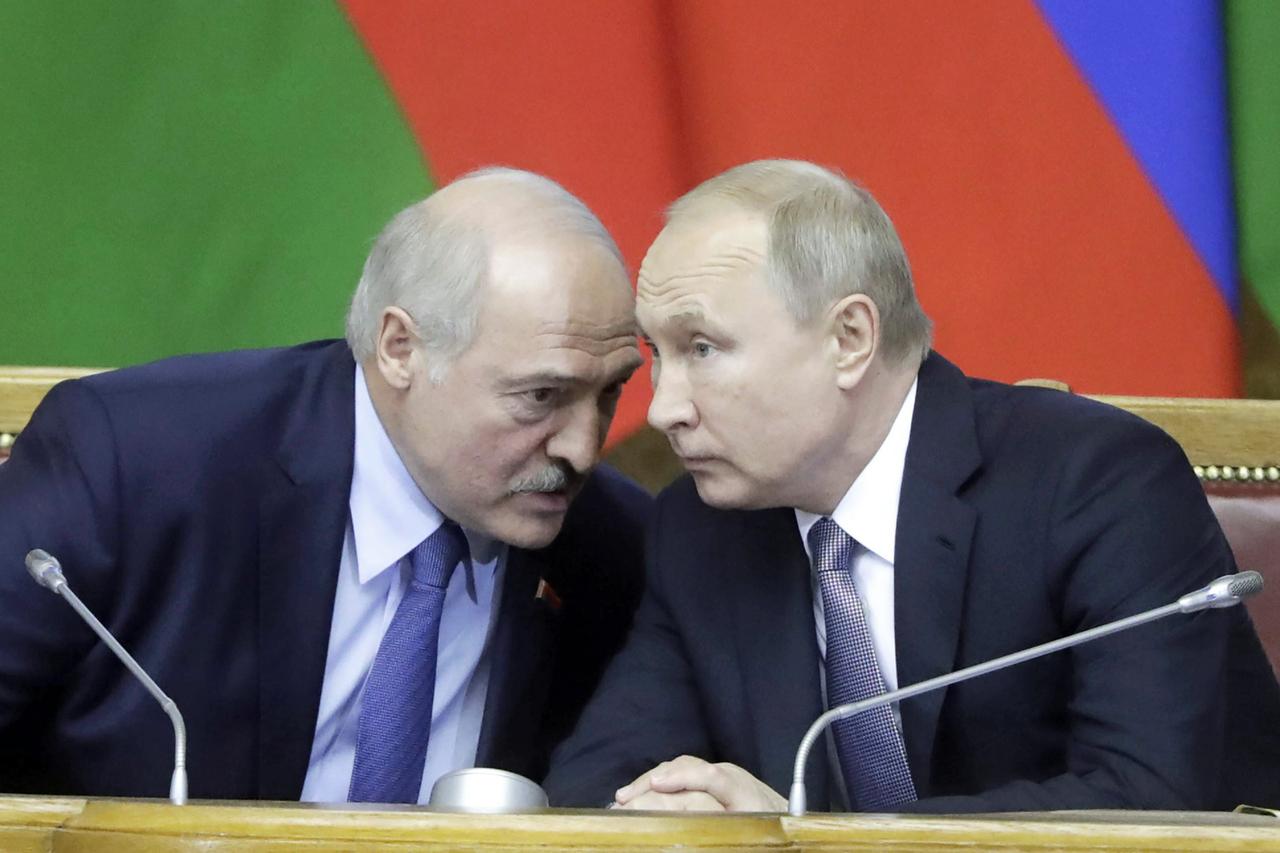 Wladimir Putin sprechen und Alexander Lukaschenko sprechen auf einem Podium leise miteinander.