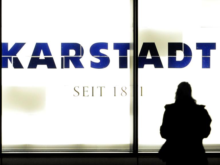Eine Frau steht in Essen vor einem beleuchteten Karstadt-Logo