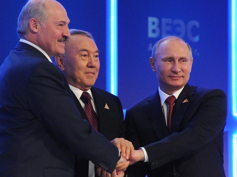 Weißrusslands Präsident Lukaschenko, Kasachstans Präsident Nasarbajew und der russische Präsident Putin legen ihre Hände übereinander.