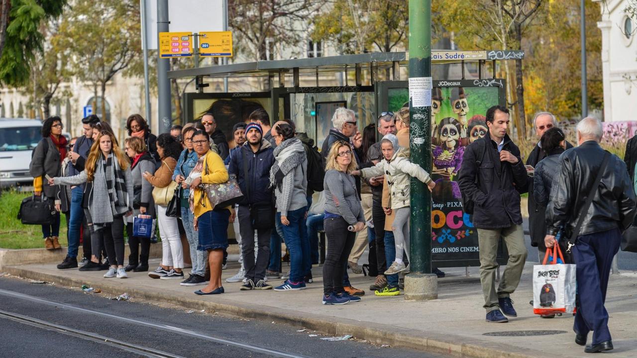 Menschen stehen an einer Bushaltestelle in Lissabon