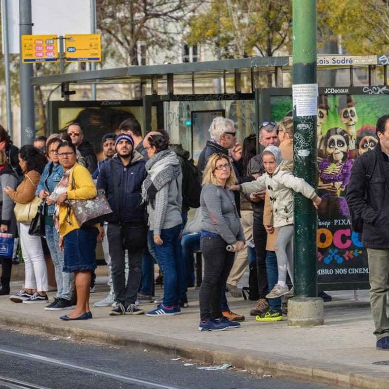 Menschen stehen an einer Bushaltestelle in Lissabon