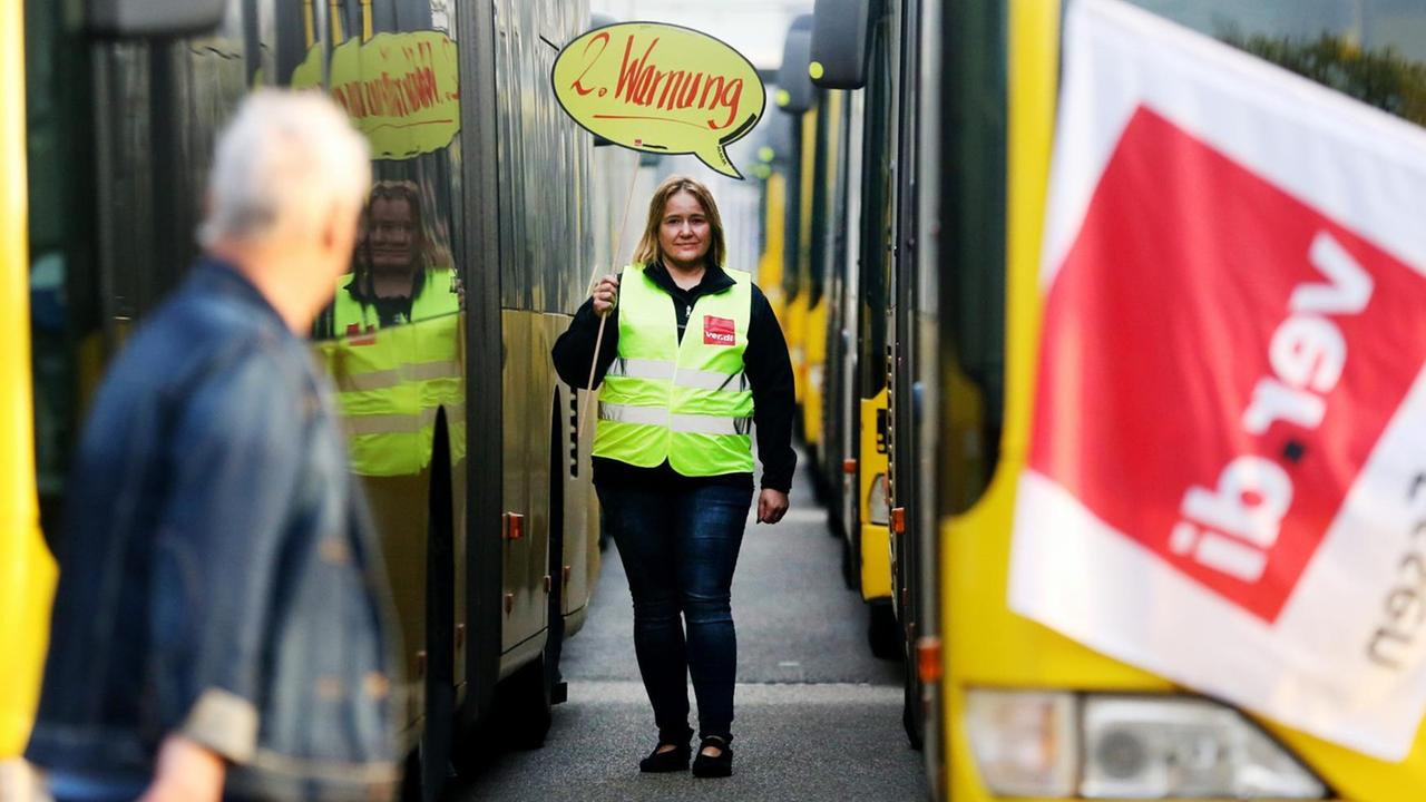 Eine Busfahrerin der Ruhrbahn protestiert mit einem Transparent "2. Warnung".