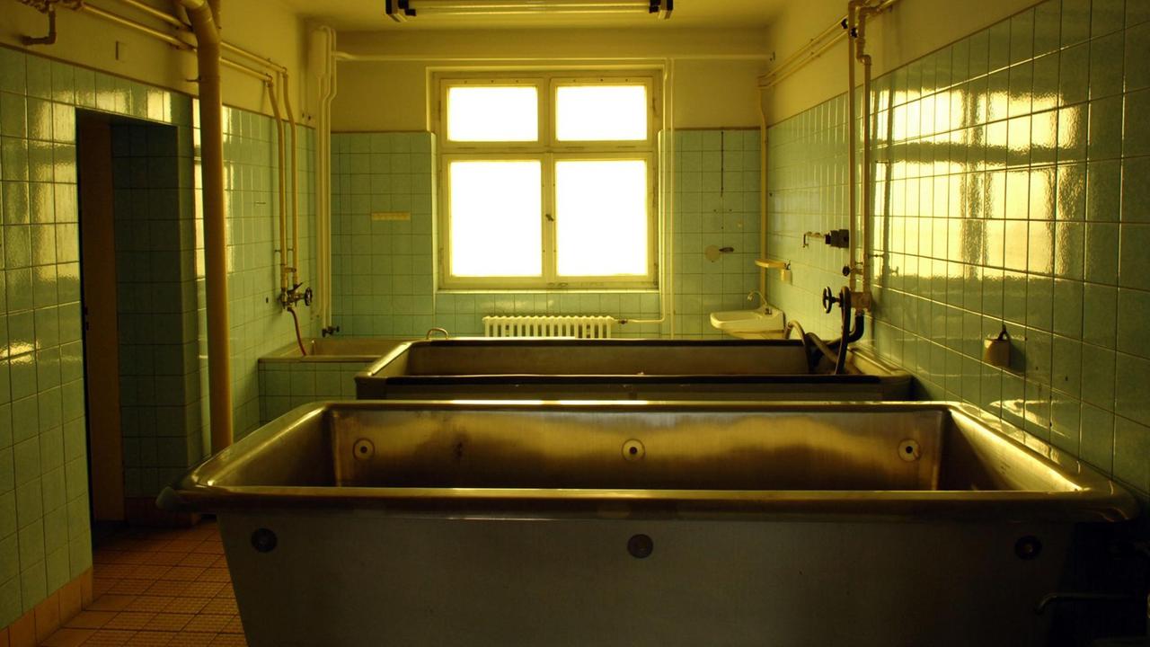 Ein Behandlungszimmer des Haftkrankenhauses der Stasi in Berlin Hohenschönhausen. In dem blau gekachelten Untersuchungsraum stehen mehrere Metallwannen.