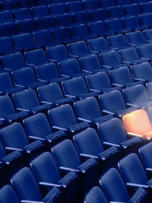 Ein leerer Theatersaal mit einem Spotlight auf einen einzelnen Sitz.