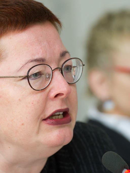 Ein Porträt von Martina Weyrauch, der Leiterin der Brandenburgischen Landeszentrale für politische Bildung. Im Hintergrund ist unscharf eine Frau mit Brille zu sehen.
