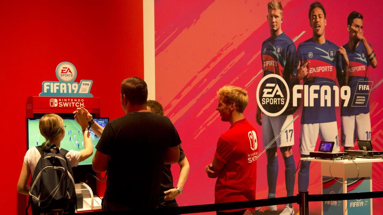 Messe-Besucher spielen das Spiel FIFA19 am Bildschirm
