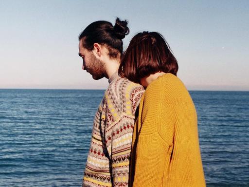 Mann und Frau in bunten Pullovern am Meer Mann und Frau in bunten Pullovern am Meer