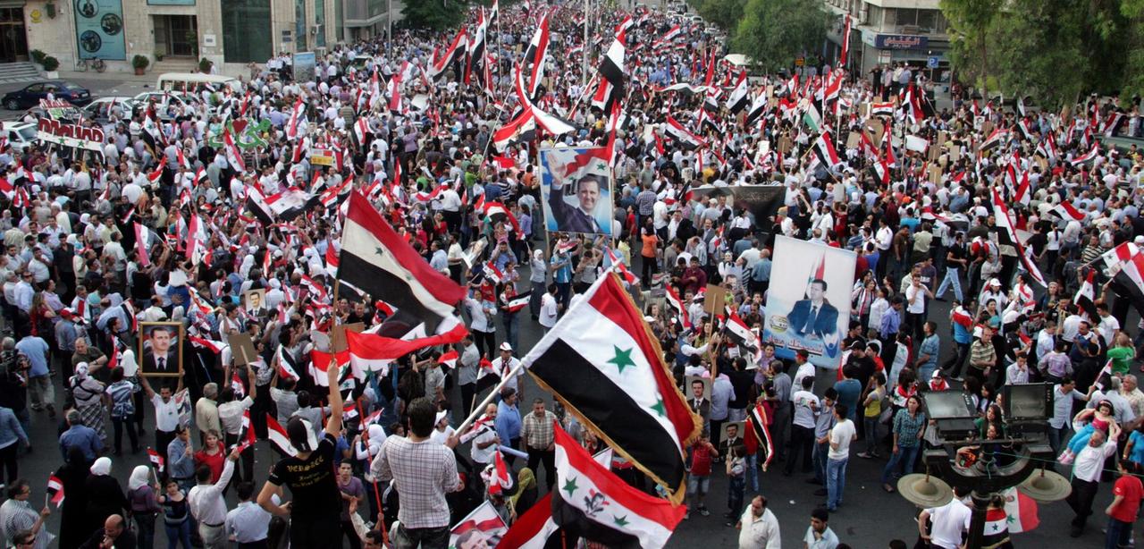 Demonstranten auf dem Hijaz-Platz in Damaskus schwenken Fahnen