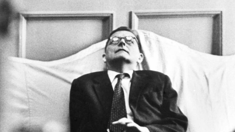 Dmitry Schostakowitsch sitzt mit zurückgeworfenem Kopf auf einem Sofa. 