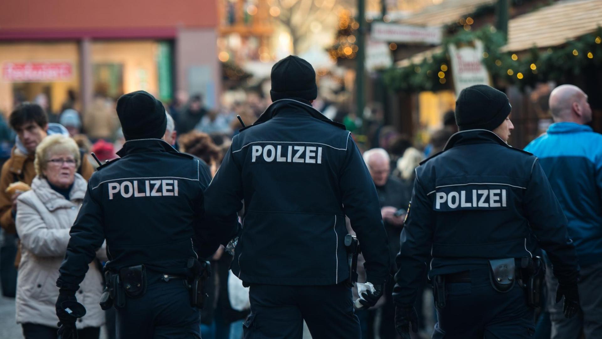 Drei Polizisten patrouillieren am in Mainz über den Weihnachtsmarkt.