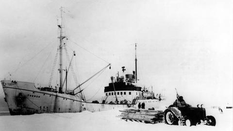 Sir Edmund Hillary, auf Traktor sitzend, entlädt am 3. März 1958 das Versorgungsschiff "Theron" in der Scott Base, wo die Commonwealth Trans-Antarctic Expedition (CTAE) unter Leitung von Hillary und dem Wissenschaftler Vivian Fuchs einen Tag zuvor erfolgreich abgeschlossen werden konnte.