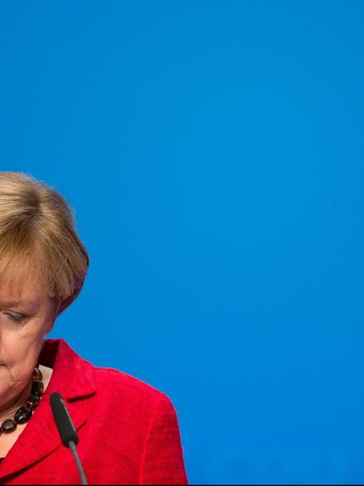 Bundeskanzlerin Angela Merkel vor einem Rednerpult; sie blickt nach unten.