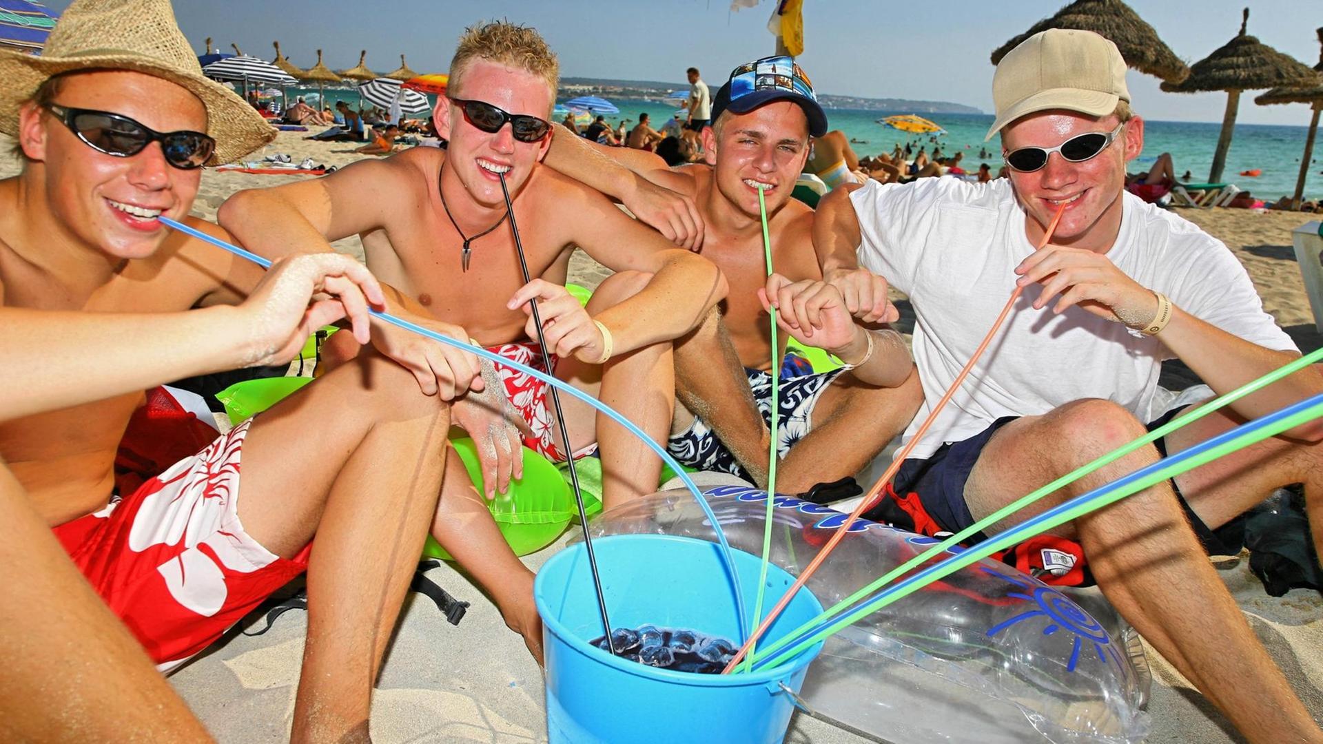 Urlauber sitzen am Badestrand von SÂArenal auf der spanischen Baleareninsel Mallorca und trinken Sangria mit Strohhalmen aus einem Eimer, aufgenommen am 28.07.2006. SÂArenal (früher auch El Arenal genannt) ist ein weitestgehend künstlich angelegter Touristenort östlich von Palma - die Hochburg des Pauschaltourismus auf Mallorca. Vor 1970 gab es hier nicht mehr als Sand, Dünen und ein paar Bäume. Mittlerweile stehen auf dem etwa sechs Kilometer langen Küstenstreifen mehr als 200 Hotels mit einer Kapazität von über 50.000 Betten. Die bei den Deutschen besonders beliebte Ferieninsel Mallorca liegt im westlichen Mittelmeer und ist mit einer Fläche von 3.624 Quadratkilometern die größte der Balearen-Gruppe. Sie verfügt über eine Küstenlinie von 398 Kilometer Länge. Foto: Andreas Lander +++(c) dpa