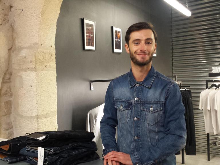 Anthony Dubos will seine Jeans in kleinen Stückzahlen, lokal und nachhaltig produzieren, um anzuknüpfen an die lange Tradition von Nîmes. Hier steht er zwischen Jeans im Verkaufsbereich.