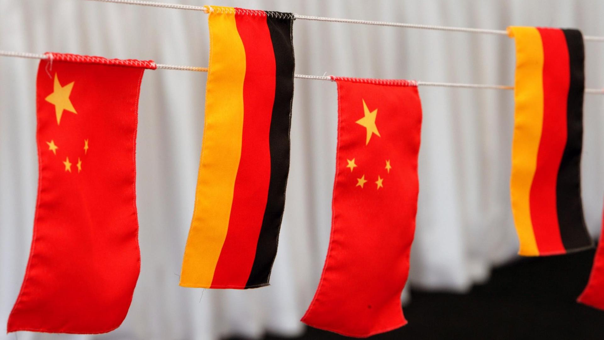 Die Fahnen von Deutschland und China hängen auf einer Bühne.