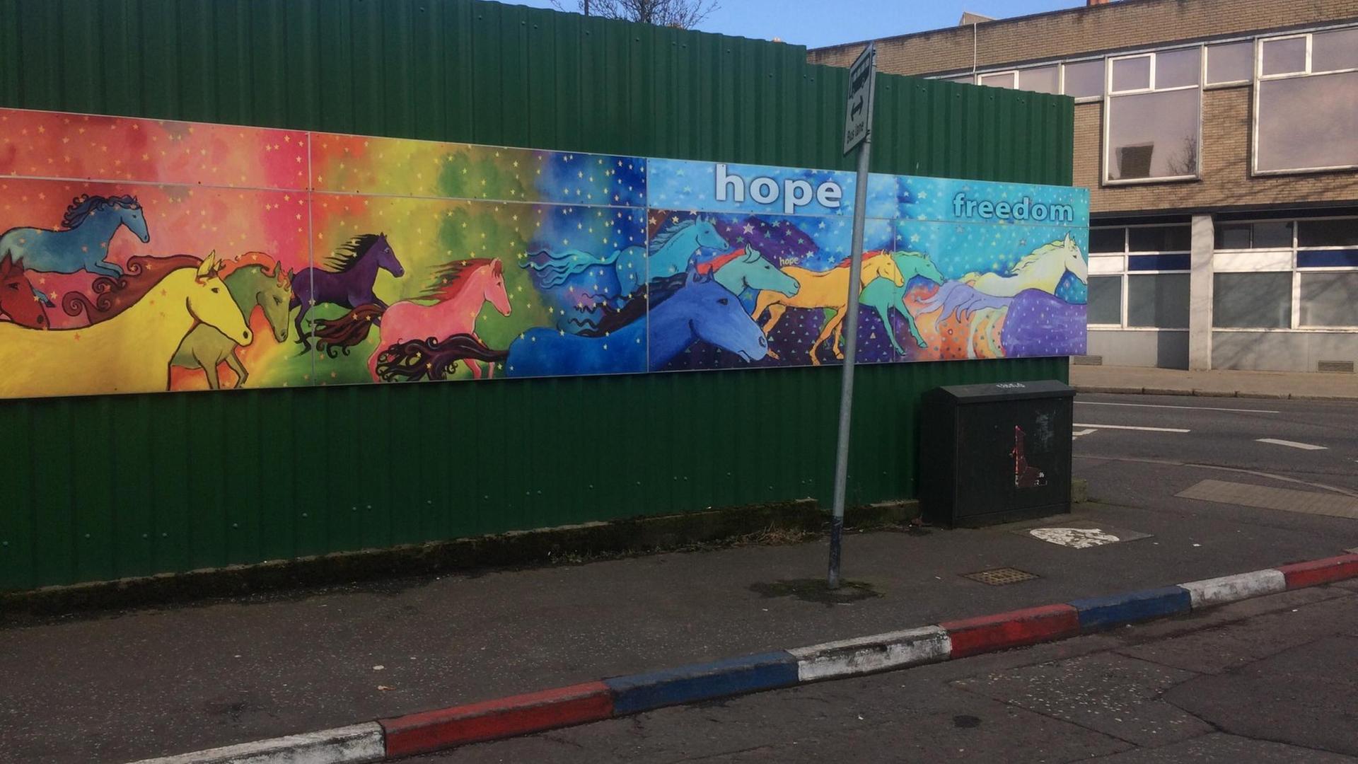 Unionisten markieren ihr Territorium im Norden Belfasts. Rot-weiß-blaue Bordsteinkante vor Streetart-Gemälde mit dem Schriftzug "hope", Hoffnung.