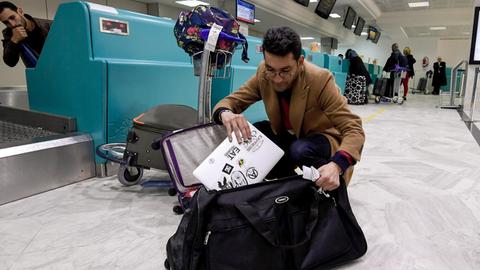 Ein Reisender aus Libyen auf dem Weg nach London verstaut am Flughafen von Tunis seinen Laptop im Koffer. Im März 2017 hatten die USA und Großbritannien eingeführt, dass Laptops oder Tablets nicht mehr als Handgepäck mitgeführt werden, wenn man aus sechs muslimischen Ländern nach Großbritannien fliegt. Foto: AFP PHOTO / FETHI BELAID