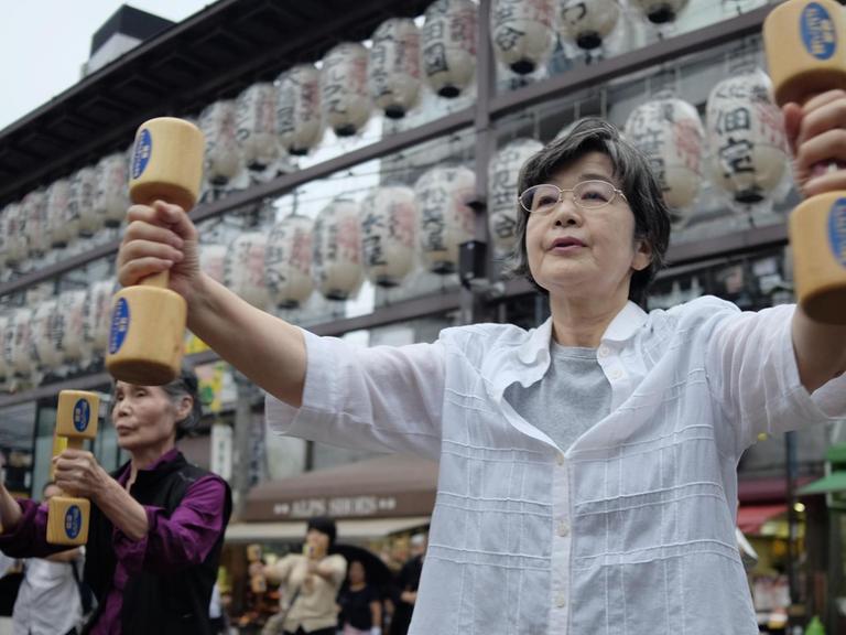 Elderly people work out with wooden dumb-bells in the grounds of a temple in Tokyo on September 19, 2016, to celebrate Japan's Respect for the Aged Day. / AFP PHOTO / KAZUHIRO NOGI