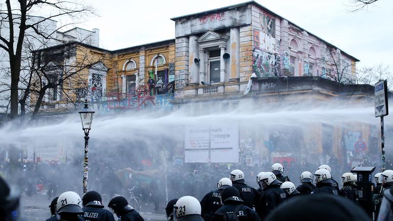 Demonstraten werden am 21.12.2013 vor dem Kulturzentrum "Rote Flora" im Schanzenviertel in Hamburg mit Wasserwerfern von der Polizei zurückgedrängt.