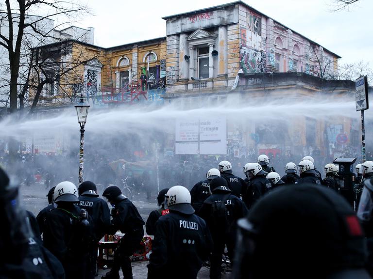 Demonstraten werden am 21.12.2013 vor dem Kulturzentrum "Rote Flora" im Schanzenviertel in Hamburg mit Wasserwerfern von der Polizei zurückgedrängt.