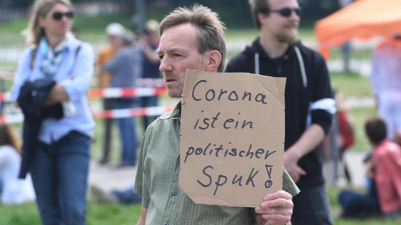 Ein Demonstrant auf der Münchner Theresienwiese. Er hält ein Schild mit der Aufschrift "Corona ist ein politischer Spuk!"
