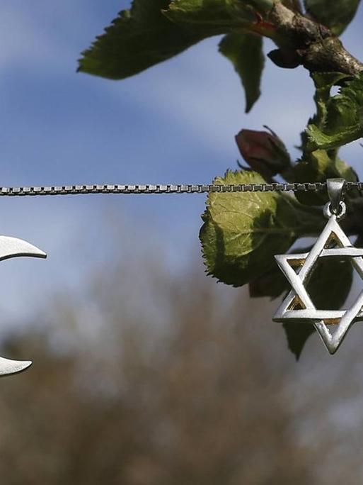 Ein Davidstern und eine Mondsichel hängen als Symbole für Judentum und Islam an einer Kette.