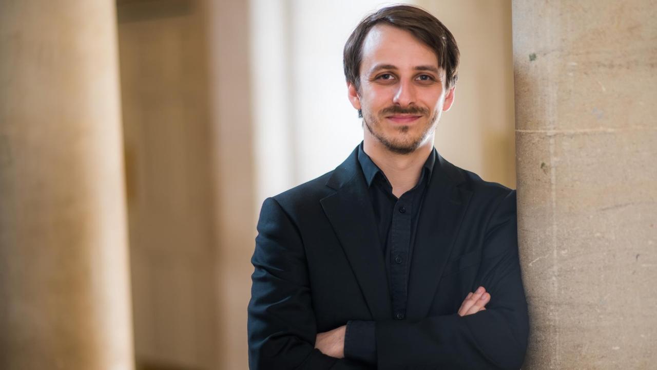 Benjamin Goodson steht lächelnd an eine Säule gelehnt.