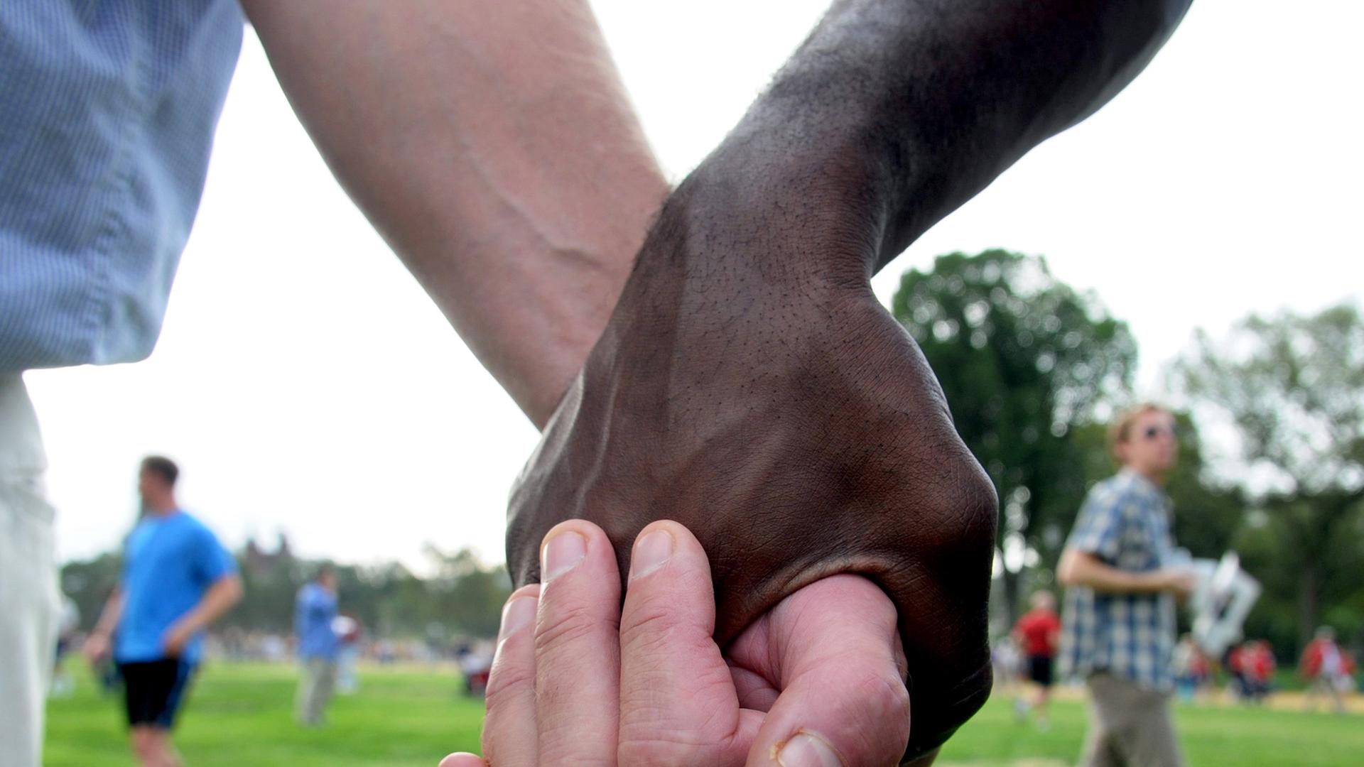 Zwei Teilnehmer einer Demonstration gegen Rassismus halten sich am 28.08.2008 in Washington an den Händen - der eine schwarz, der andere weiß.