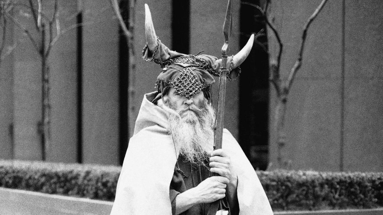 Schwarzweißfoto eines an einer New Yorker Straßenecke stehenden Mannes mit weißem wallendem Bart in Wikingerkostüm.