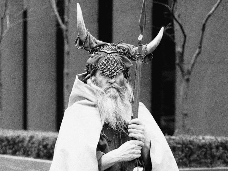 Schwarzweißfoto eines an einer New Yorker Straßenecke stehenden Mannes mit weißem wallendem Bart in Wikingerkostüm.