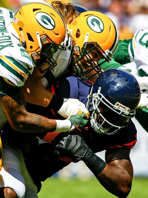 Drei Spieler der Green Bay Packers attackieren den Angriffsspieler der Chicago Bears