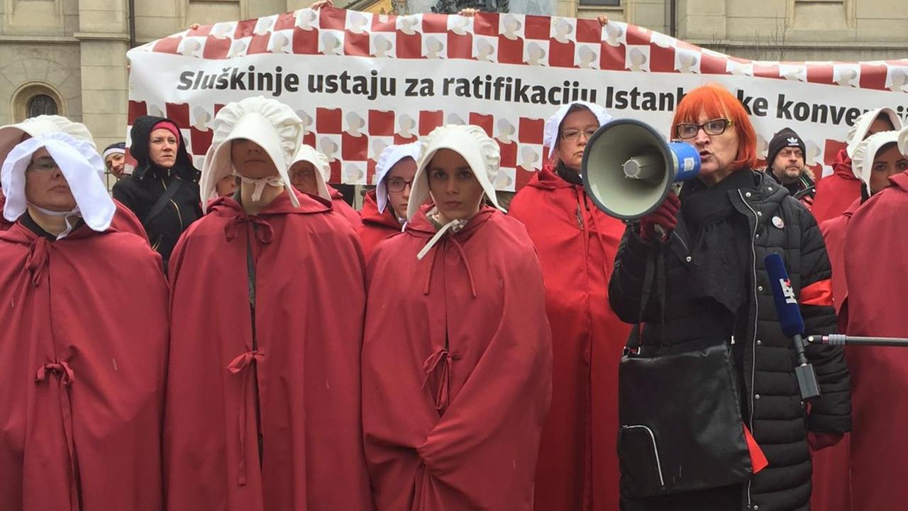 Demonstration in Zagreb für die Ratifizierung der Istanbuler Konvention gegen Gewalt an Frauen: Die roten Gewänder und weißen Kopfbedeckungen der jungen Frauen sollen christlichen Fundamentalismus symbolisieren, denn die Katholische Kirche hat sich gegen den Vertrag gestellt.